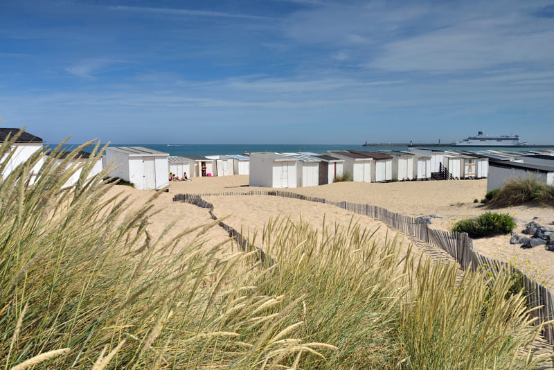 Colorful beach huts along the sandy Calais seafront promenade